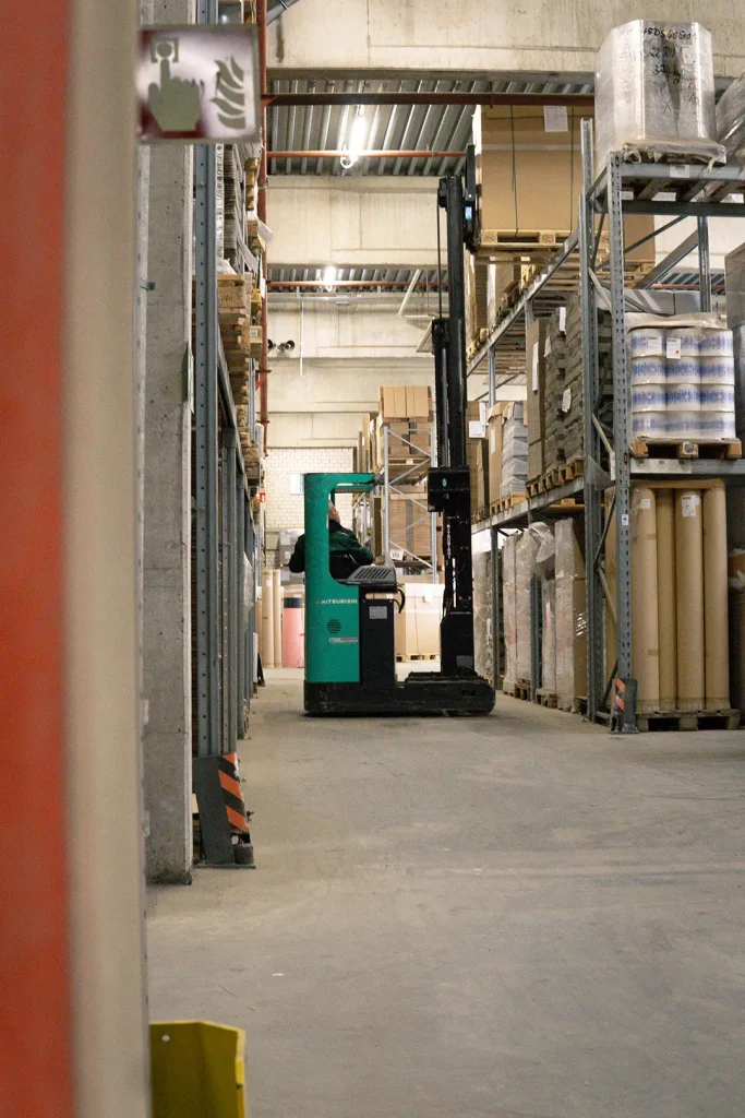 Gabelstapler zwischen Regalen mit Waren. Lagerraum mit Logistik und Waren.