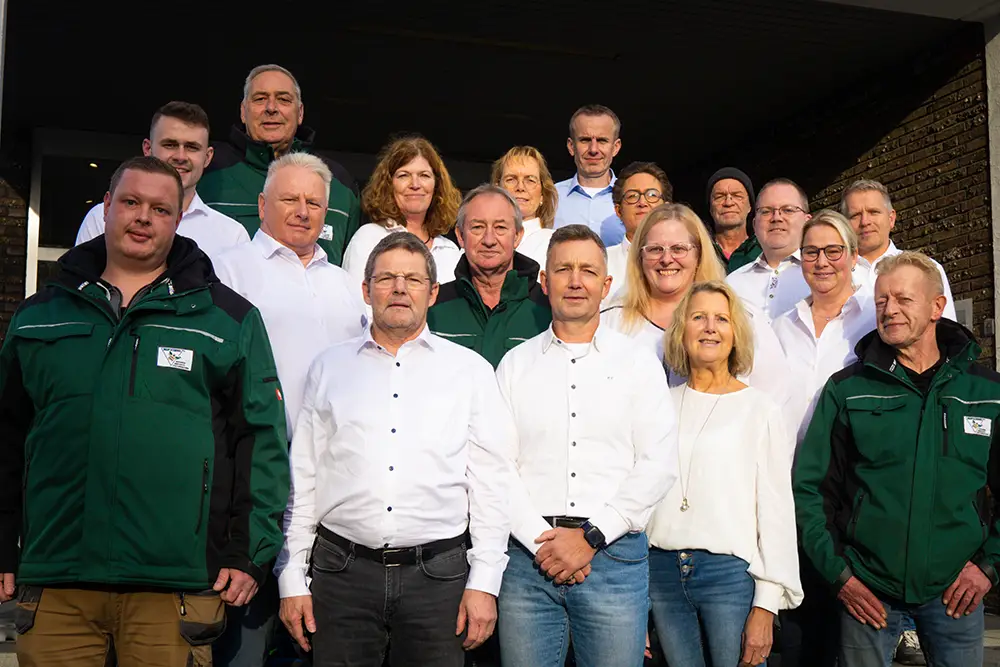 Das Hummel-Team: Gruppenfoto des Teams, einige in grünen Jacken, andere in weißen Hemden, "Über uns".
