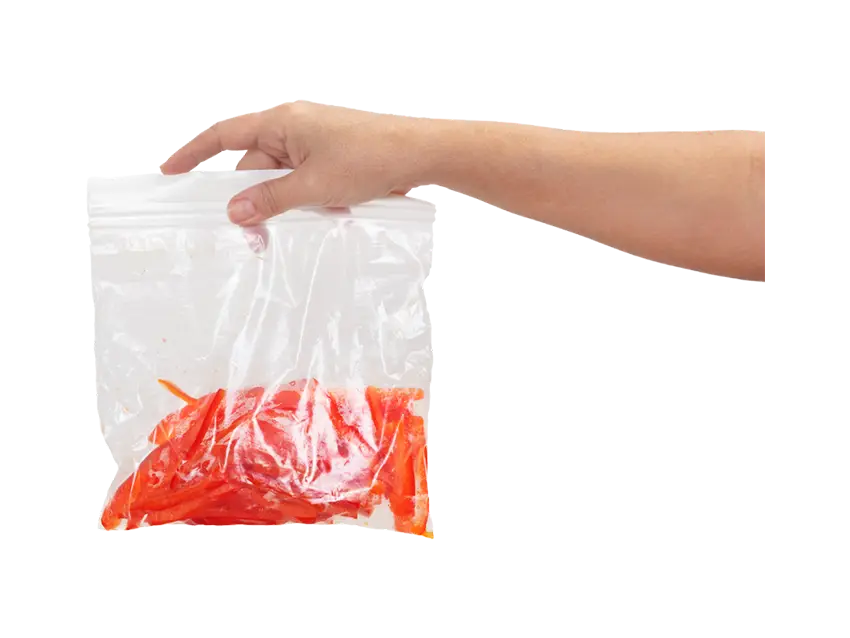 Hand holding a clear LDPE Druckverschlussbeutel (zipper bag) filled with sliced red bell peppers.